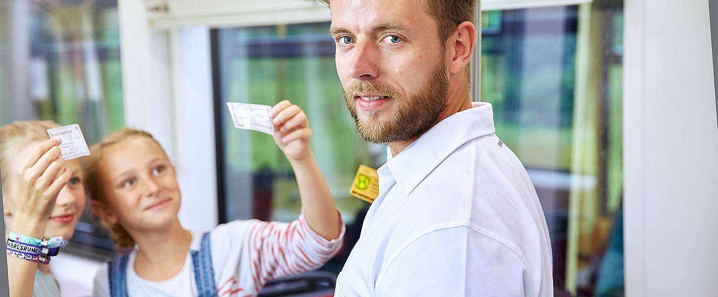 Zwei Mädchen zeigen einem Fahrscheinprüfer ihre Fahrkarten.