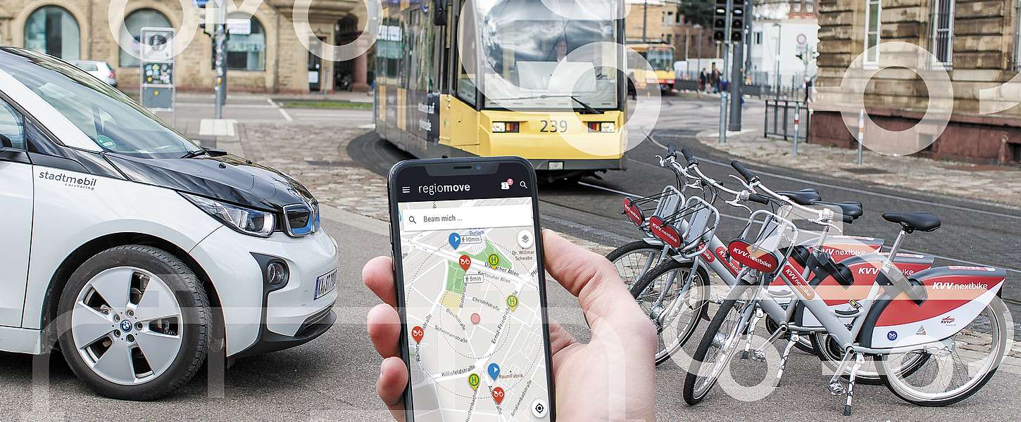 Hand mit Smartphone. Im Hintergrund Auto, Fahrräder und Bahn zu sehen.