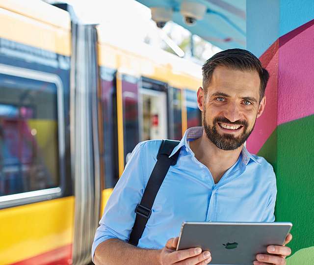 Ein Mann steht lächelnd vor einer Bahn.