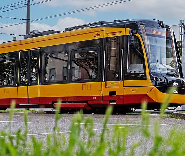 Ein Mann sitzt vor einer Wand voller Bildschirme und telefoniert. Die Bildschirme zeigen Fahrpläne.