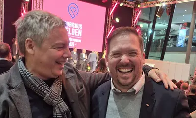 Zwei Männer lachen in die Kamera.