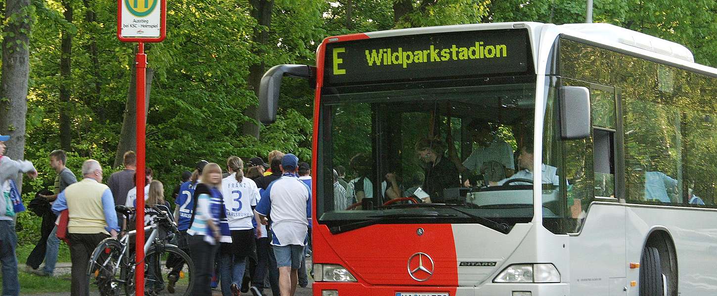 Menschen in KSC-Trikots steigen aus einem Bus am Wildparkstadion.