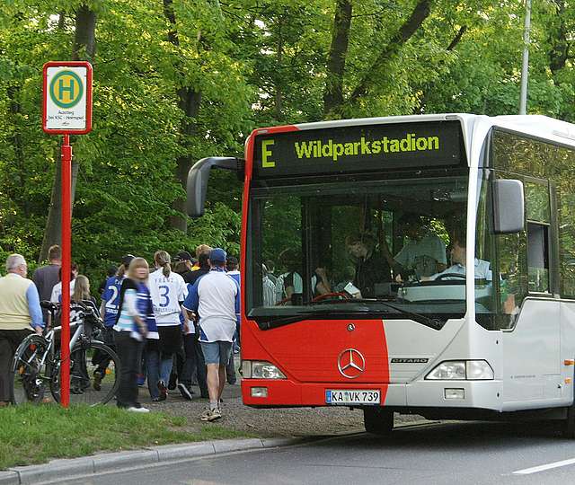 Menschen in KSC-Trikots steigen aus einem Bus am Wildparkstadion.