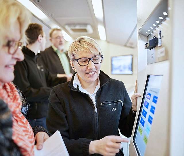 Eine KVV-Mitarbeiterin zeigt einer Kundin etwas auf dem Bildschirm eines Fahrscheinautomats.