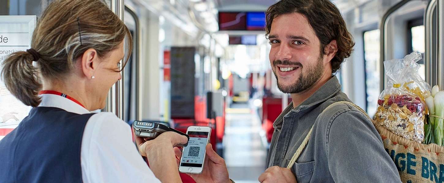 Mann zeigt einer Kontrolleurin seine Fahrkarte auf dem Smartphone.