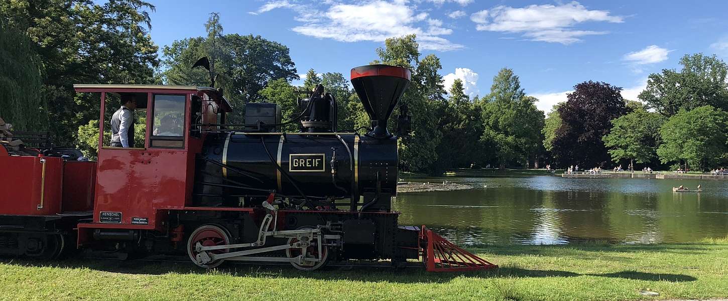 Die Schlossgartenbahn fährt an einem sonnigen Tag durch den Schlossgarten.