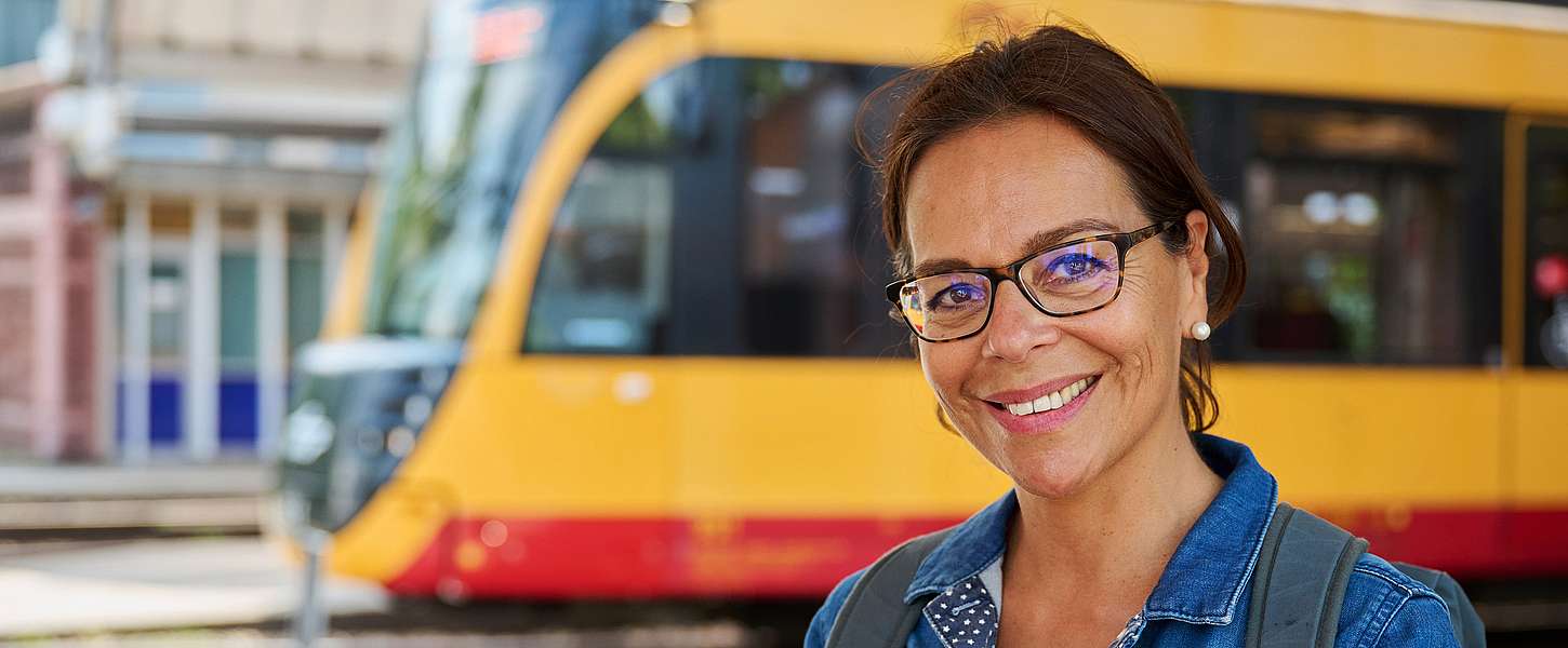 Eine junge Frau sitzt im Bus und schaut lachend über ihre Schulter nach hinten.