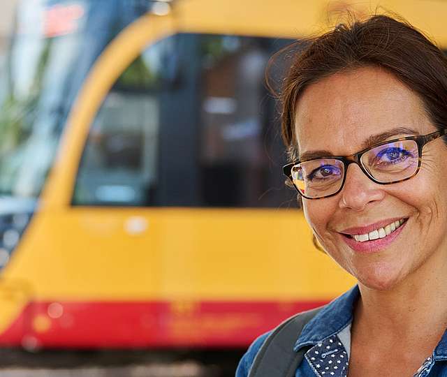 Eine junge Frau sitzt im Bus und schaut lachend über ihre Schulter nach hinten.