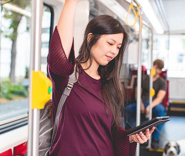 Frau in Bahn schaut auf Handy