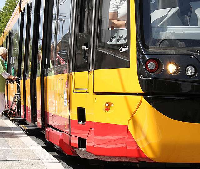 Zwei Frauen steigen in eine Niederflurbahn ein. Eine der Frauen hat einen Rollator.