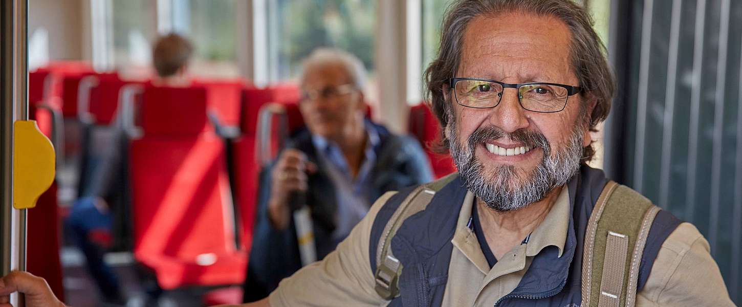 Ein älterer Mann mit Rucksack steht in der Bahn.