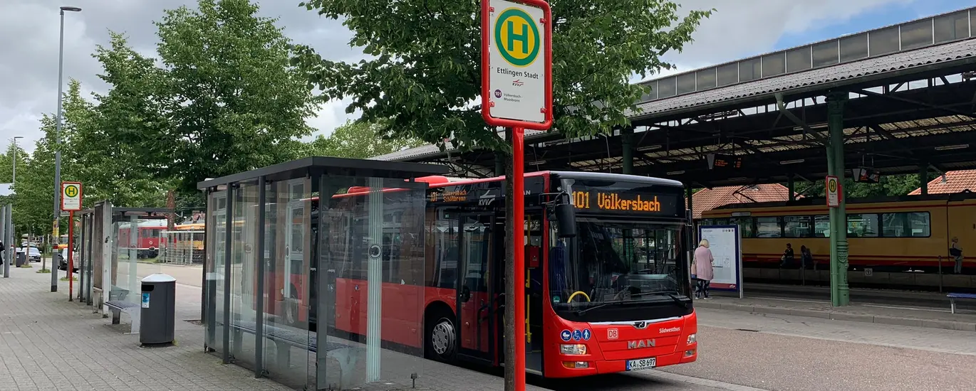 Ein Bus in roter Farbe der Linie 101 von Ettlingen nach Völkersbach steht an der Haltestelle Ettlingen Bahnhof. 