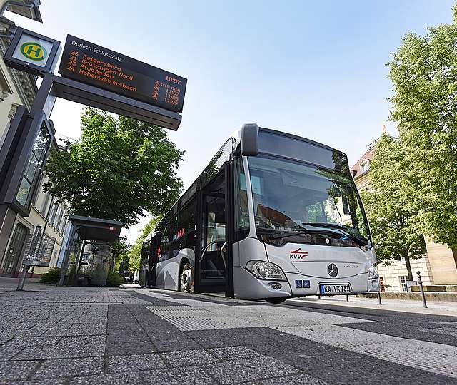 Ein Bus des KVV steht an einer Bushaltestelle.